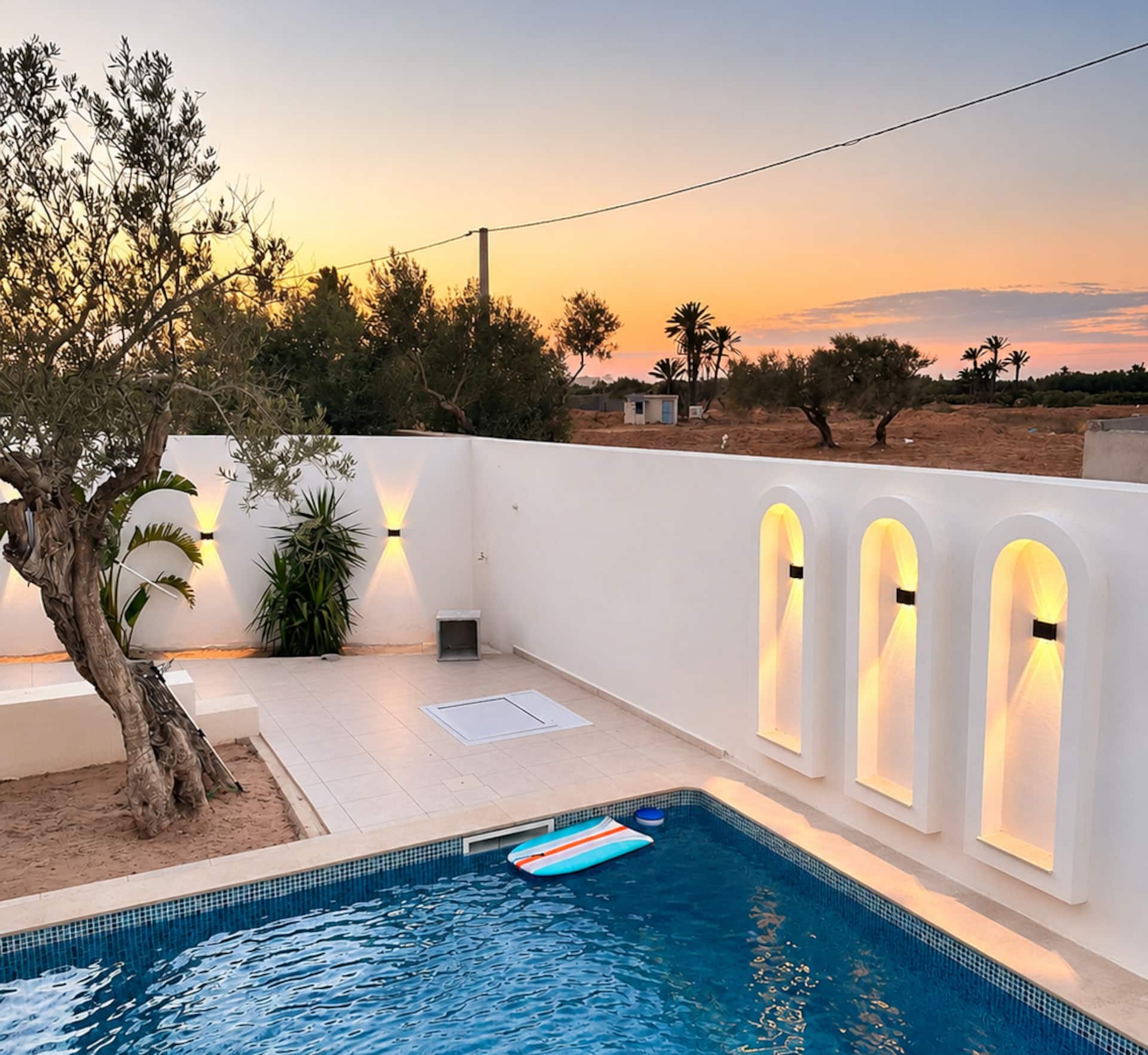 Piscina e archi luminosi di fronte all’oliveto al tramonto