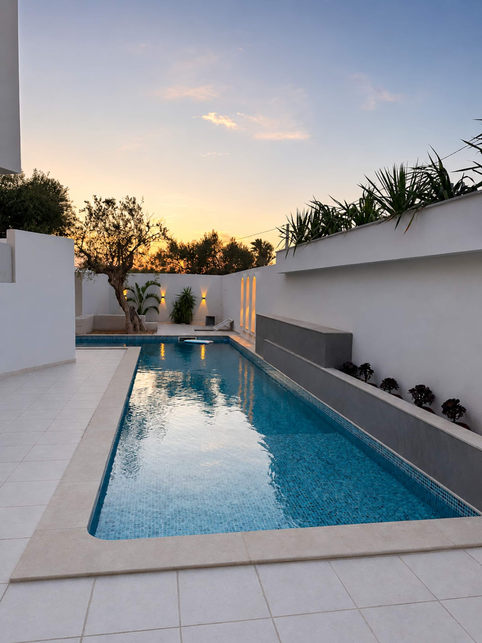 Lunga piscina turchese al tramonto con terrazza in pietra